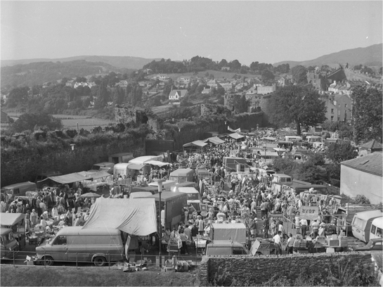 Llun awyr du a gwyn o'r dref, yn dangos llawer o bobl a cherbydau wedi ymgynnull i fynychu Ffair Fêl Conwy.