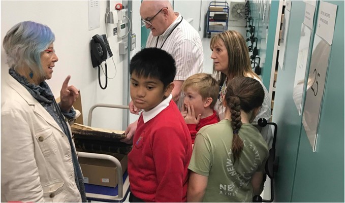 Mae pobl ifanc yn cael eu dangos o amgylch storfa'r archif